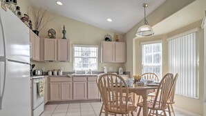 A kitchen with wooden cabinets, a refrigerator, a stove, and a dining table with chairs.