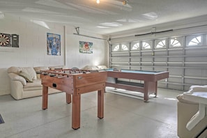 Une pièce équipée d’un baby-foot, d’une table de billard, d’un canapé et d’un jeu de fléchettes.