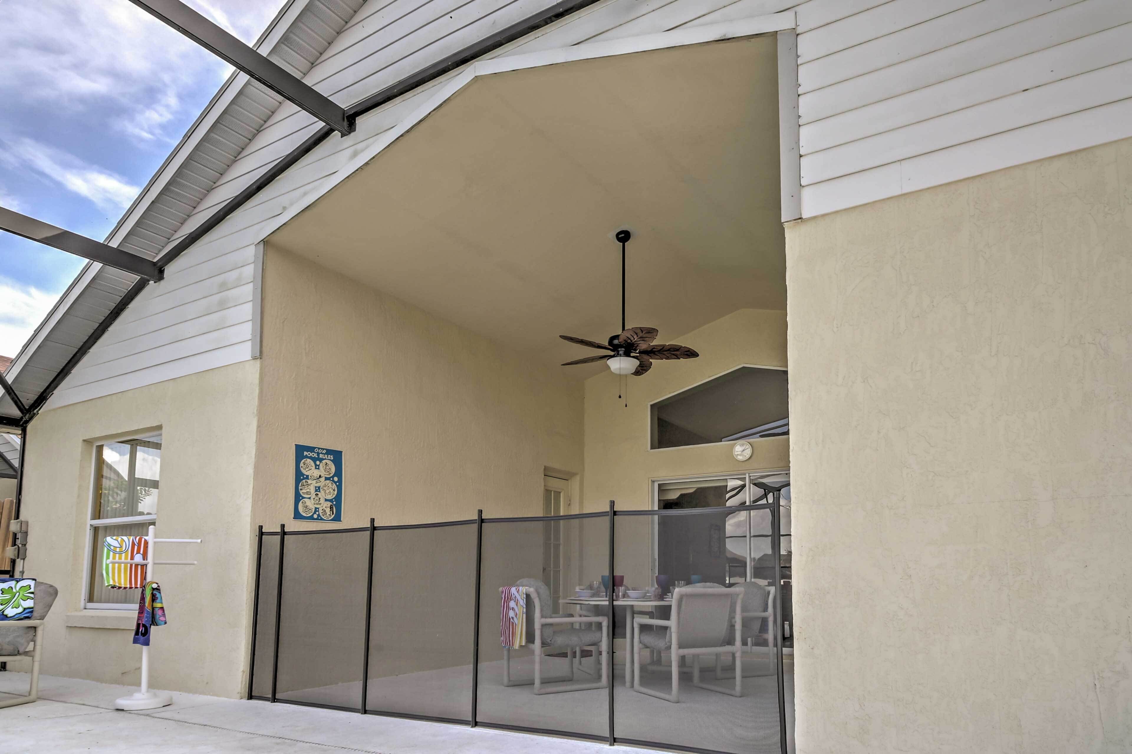 Ein überdachter Patio-Bereich mit Deckenventilator, Tisch und Stühlen sowie Blick auf den Pool.