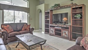 A living room with a leather sofa, a coffee table, and a TV stand with shelves.