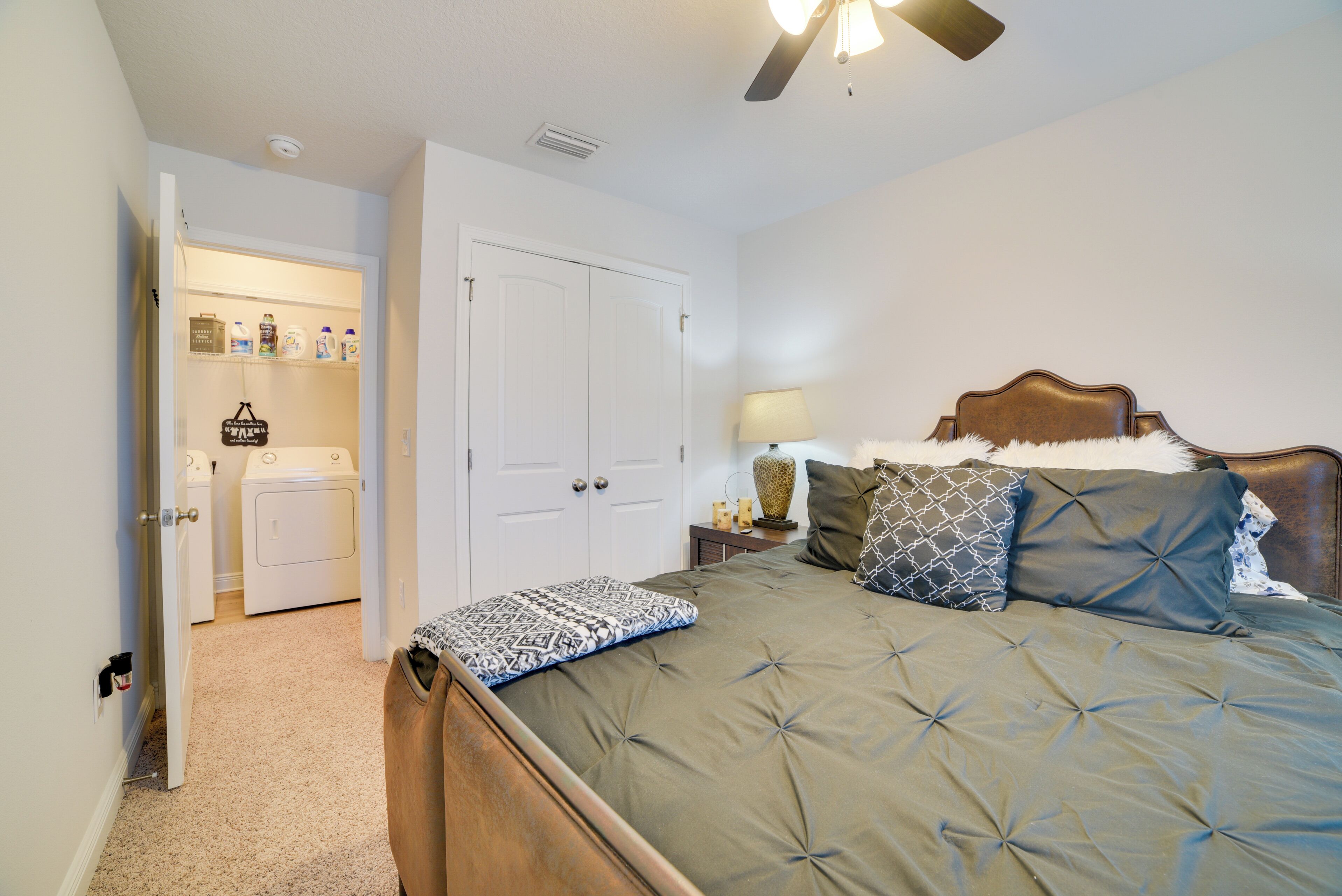 A bedroom with a bed, a nightstand with a lamp, a dresser, and a closet.