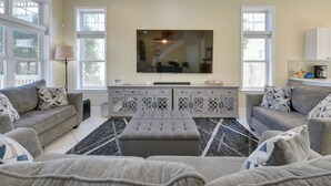 A modern living room with a large flat-screen TV, grey sofas, and a patterned rug. - Breathtaking Santa Rosa Beach Home < 1 Mi to Gulf! (Santa Rosa Beach)
