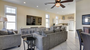 A spacious living room with a grey sofa set, a small round table, and a ceiling fan. - Breathtaking Santa Rosa Beach Home < 1 Mi to Gulf! (Santa Rosa Beach)