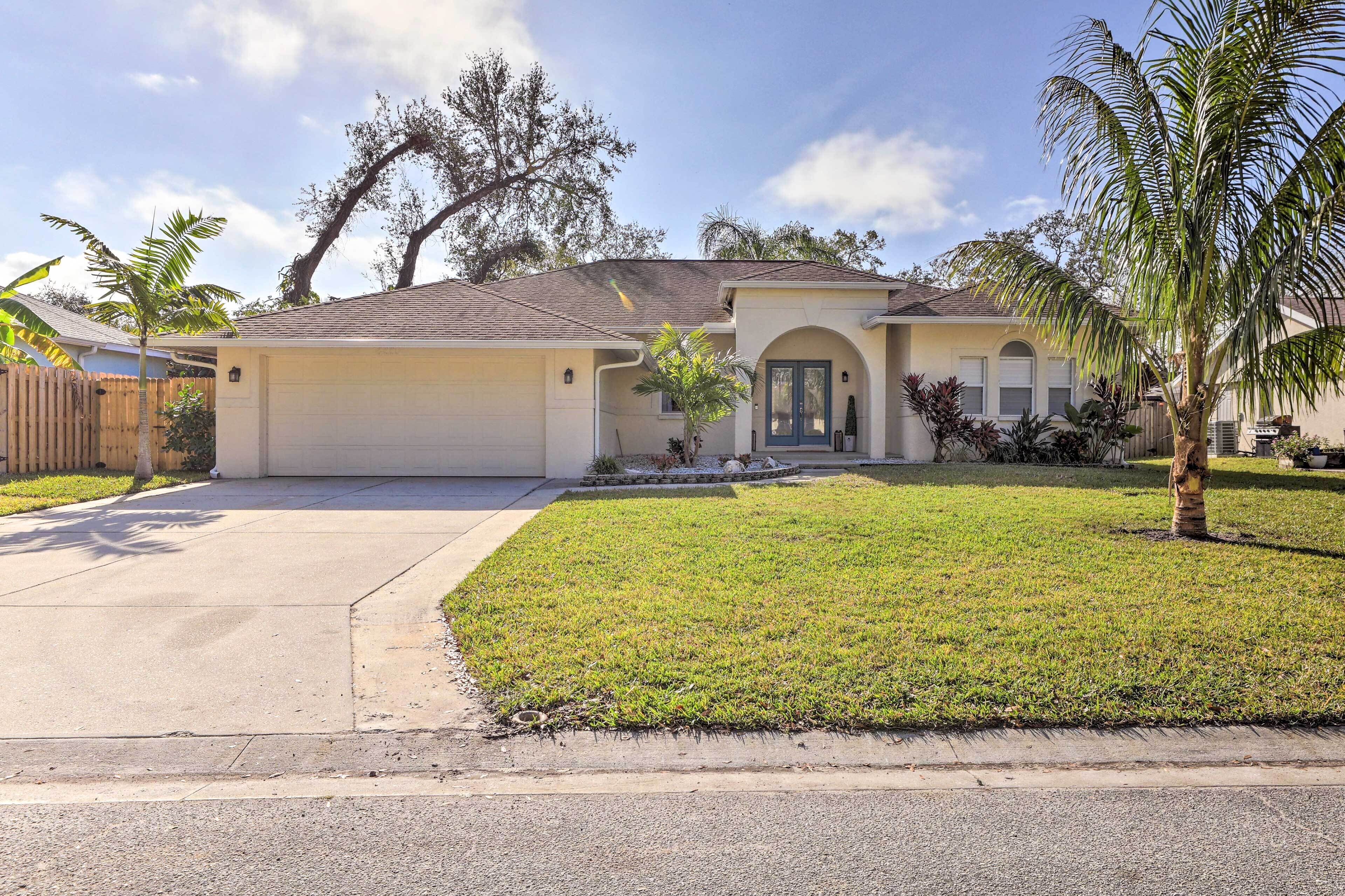 A single-story house with a front garage, a well-maintained lawn, and a palm tree.