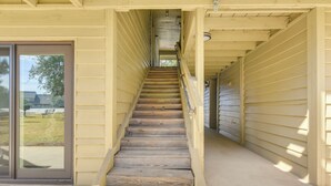 A wooden staircase leading to a covered area with a sliding glass door on the left.