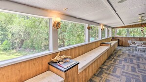 A long bench with a wooden finish along a wall with large windows, a small table with decorative items, and a patterned carpet. - Bright Steinhatchee Home: Proximity to Ocean! (Steinhatchee)