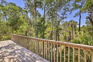 A wooden deck with a railing overlooking a dense forest with various trees and shrubs. - Bright Steinhatchee Home: Proximity to Ocean! (Steinhatchee)