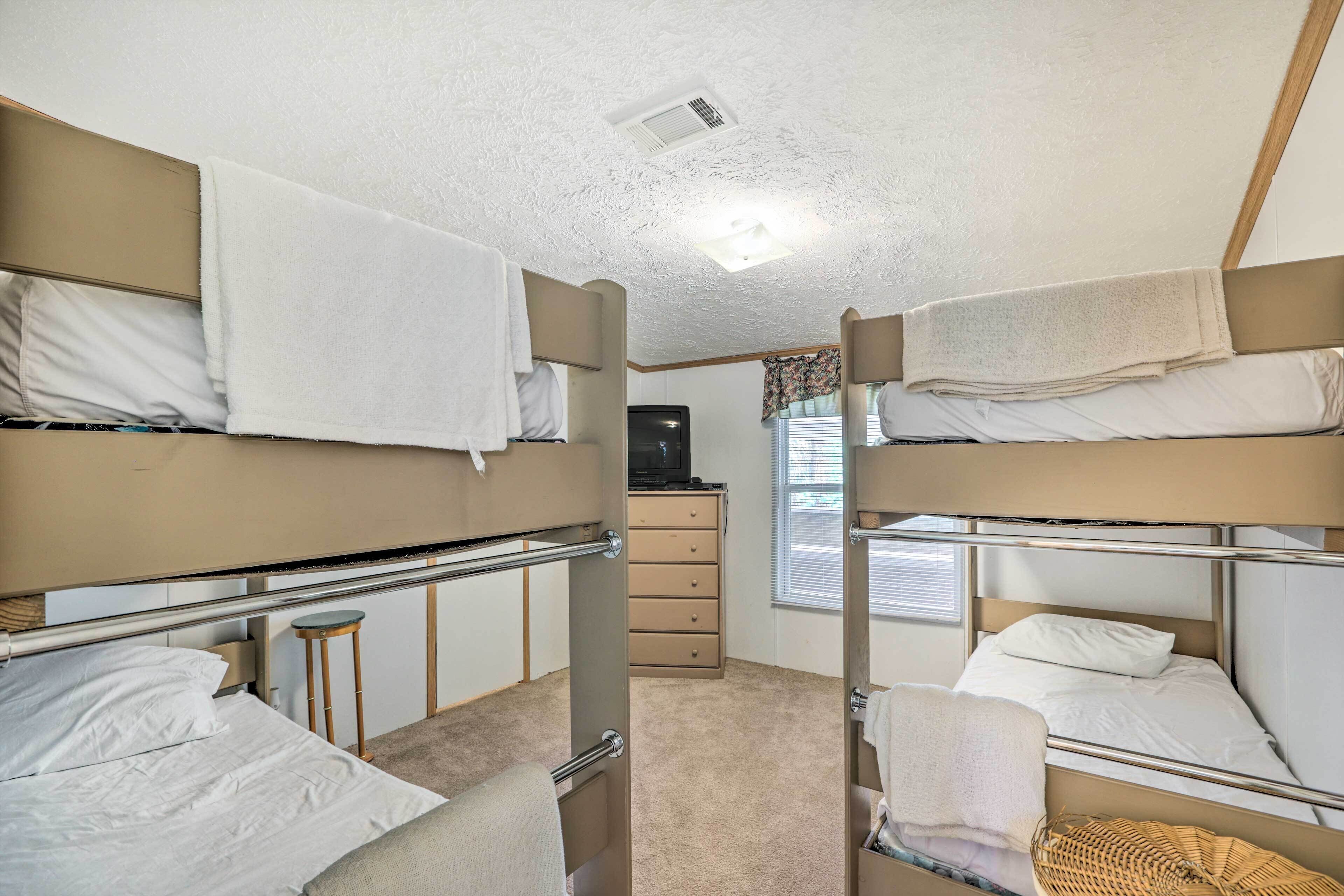 Une chambre avec un lit superposé, une commode et un téléviseur.