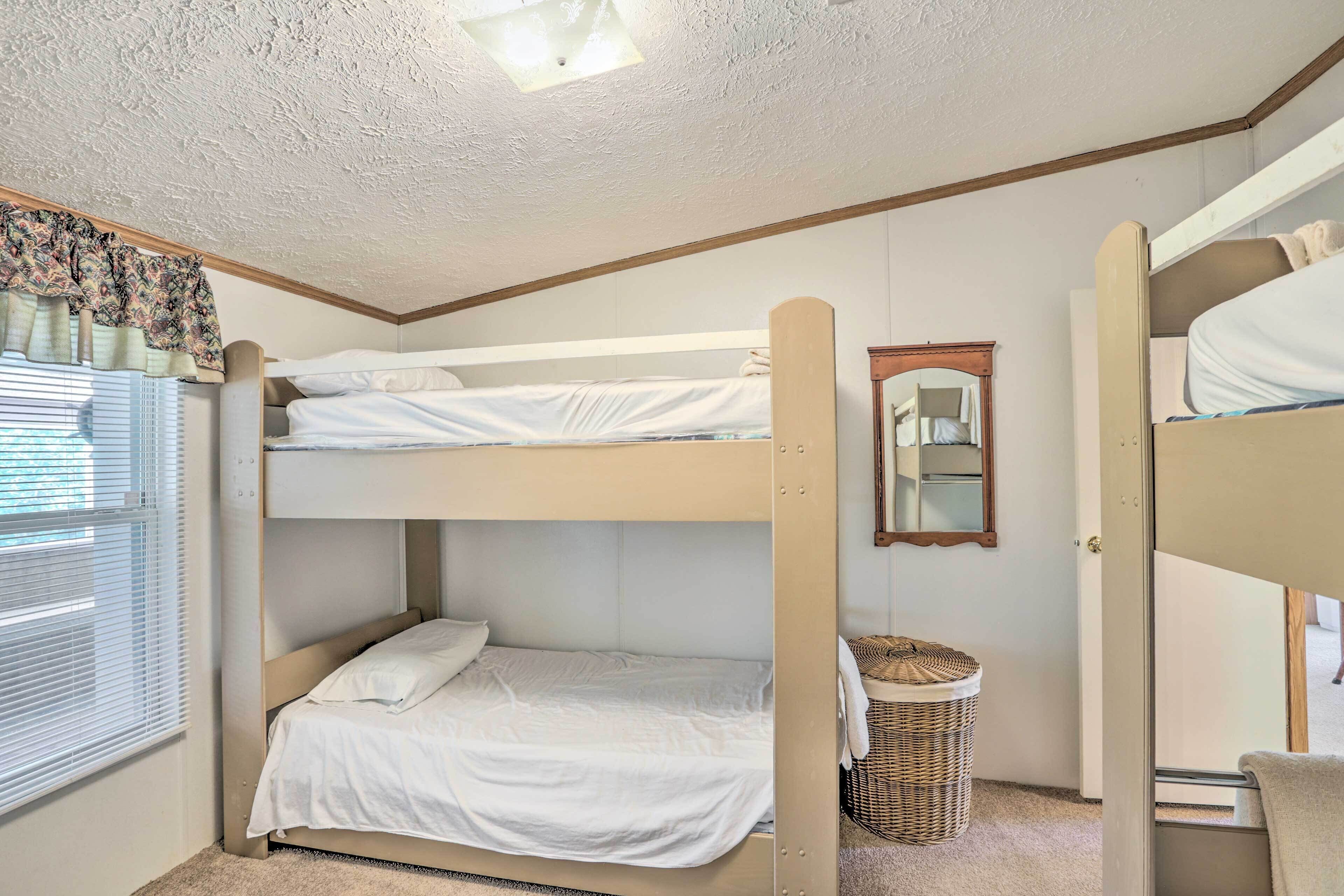 A bunk bed room with a window, a mirror, and a wicker basket.
