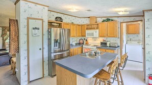 A compact kitchen with wooden cabinets, a stainless steel refrigerator, a microwave, and a sink. - Bright Steinhatchee Home: Proximity to Ocean! (Steinhatchee)