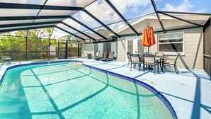 Piscina coberta com área de terraço, incluindo mesa e cadeiras, e vista para o quintal.