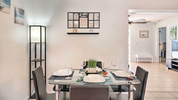 Un coin repas avec une table en verre, des chaises noires et une photo de famille encadrée accrochée au mur.