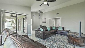 A spacious living room with a large sectional sofa, a round coffee table, and a ceiling fan.