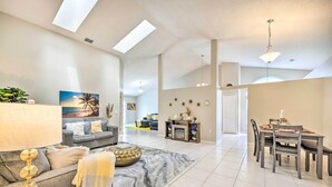 A spacious living room with a sofa, coffee table, and a dining area with chairs and a table. - Private Pool & Yard: Airy Kissimmee Retreat! (Poinciana)