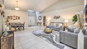 A spacious living area with a high ceiling, a dining table with chairs, a sofa, and a coffee table. - Private Pool & Yard: Airy Kissimmee Retreat! (Poinciana)