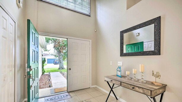 A hallway with a wooden console table, a mirror, and a door leading outside. - Private Pool & Yard: Airy Kissimmee Retreat! (Poinciana)