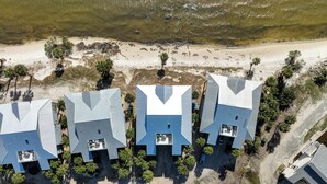 Eine Reihe moderner Gebäude mit blauen Dächern und einem zentralen Innenhof, neben einem Sandstrand und einem Gewässer.