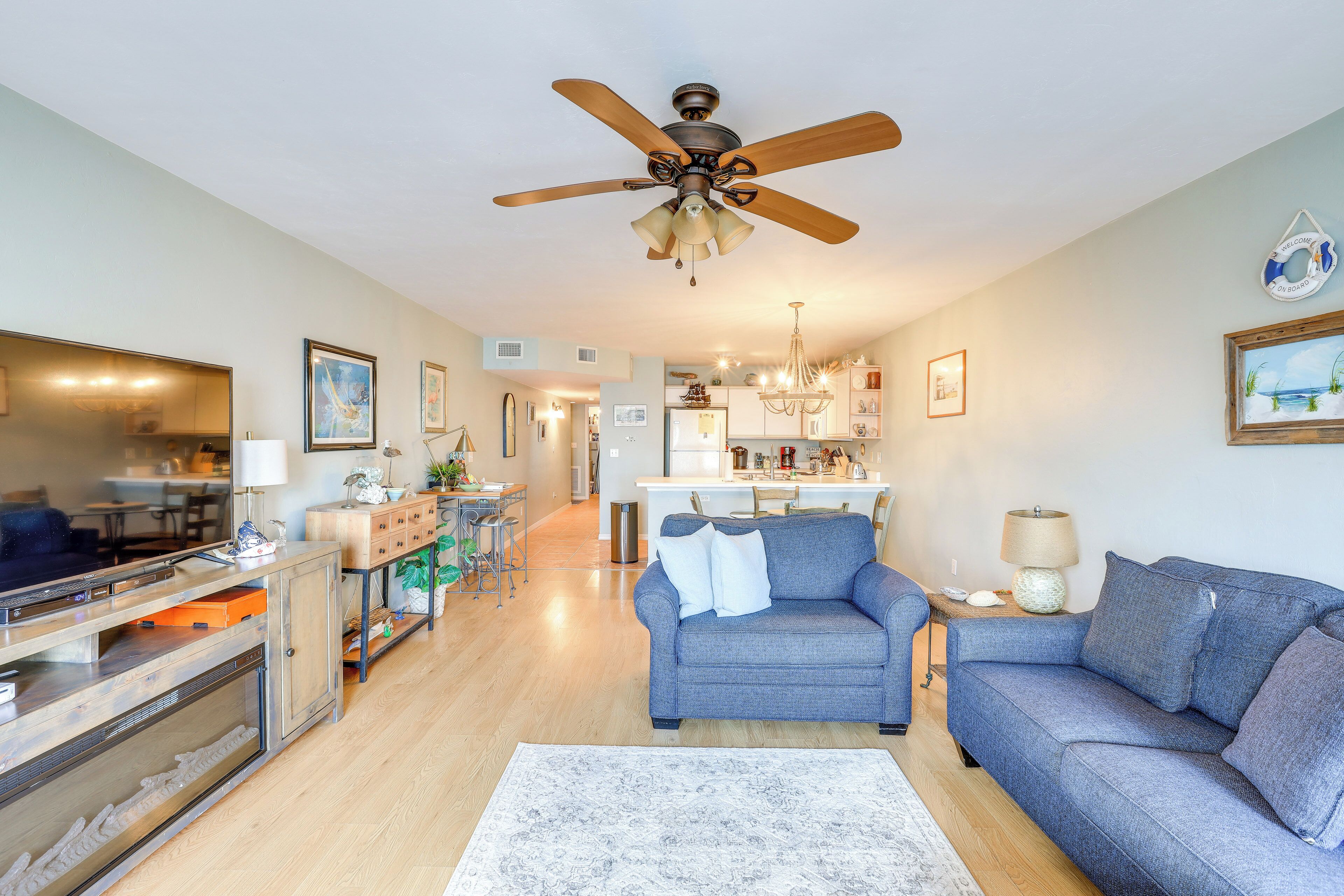 A modern living room with a blue sofa, a wooden coffee table, and a ceiling fan.