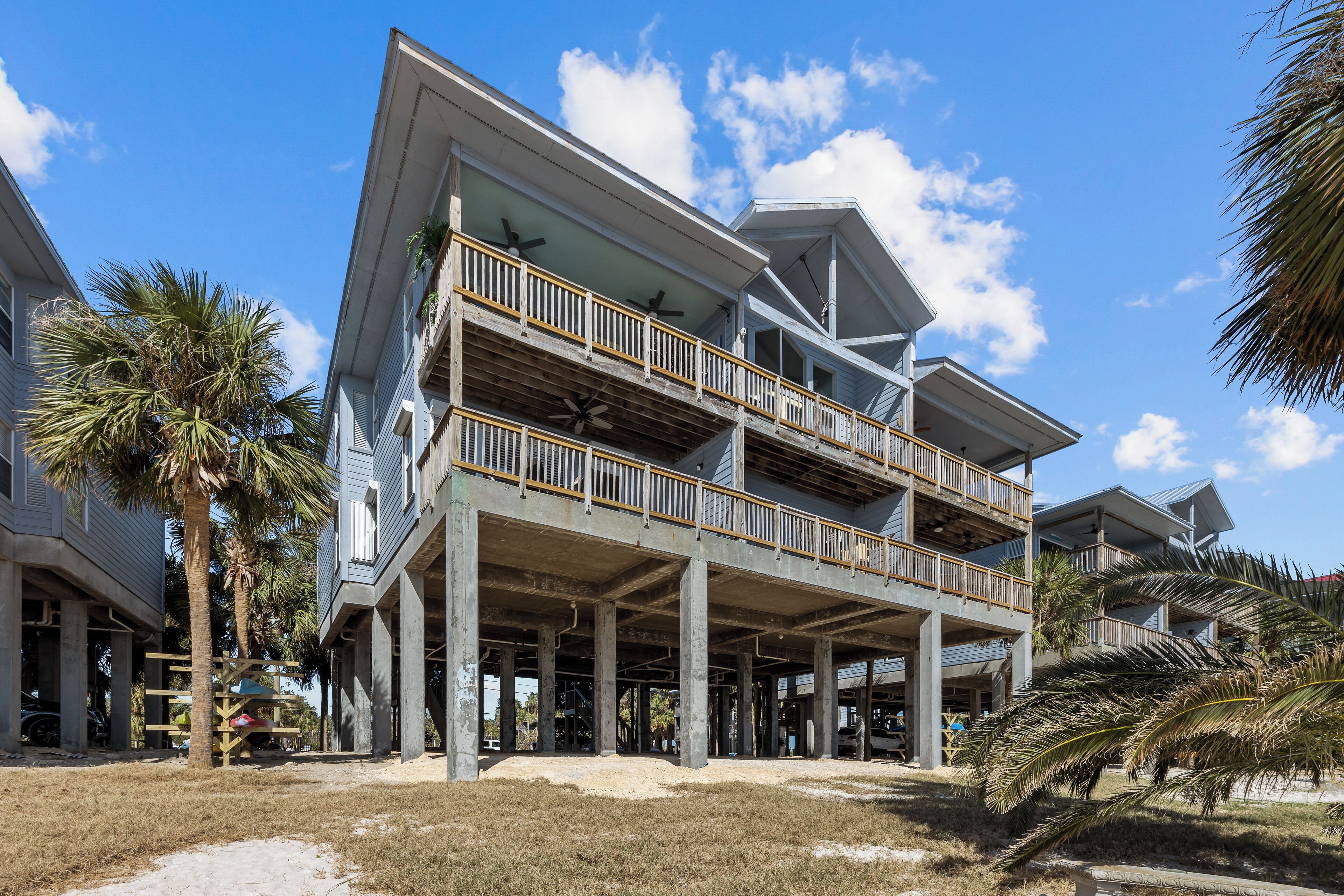 A multi-story building with balconies, a covered outdoor area, and palm trees.