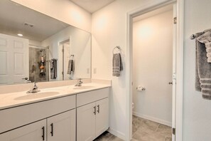 A modern bathroom with two sinks, a large mirror, and a shower.