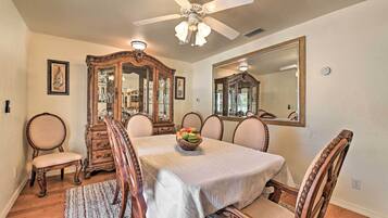 A dining room with a large table, six chairs, a wooden cabinet, and a ceiling fan.