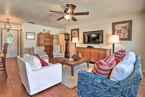 A living room with a ceiling fan, a television, a wooden coffee table, and a blue patterned sofa. - Central Florida Escape on 5 Acres w/ Grill & Pool! (Umatilla)