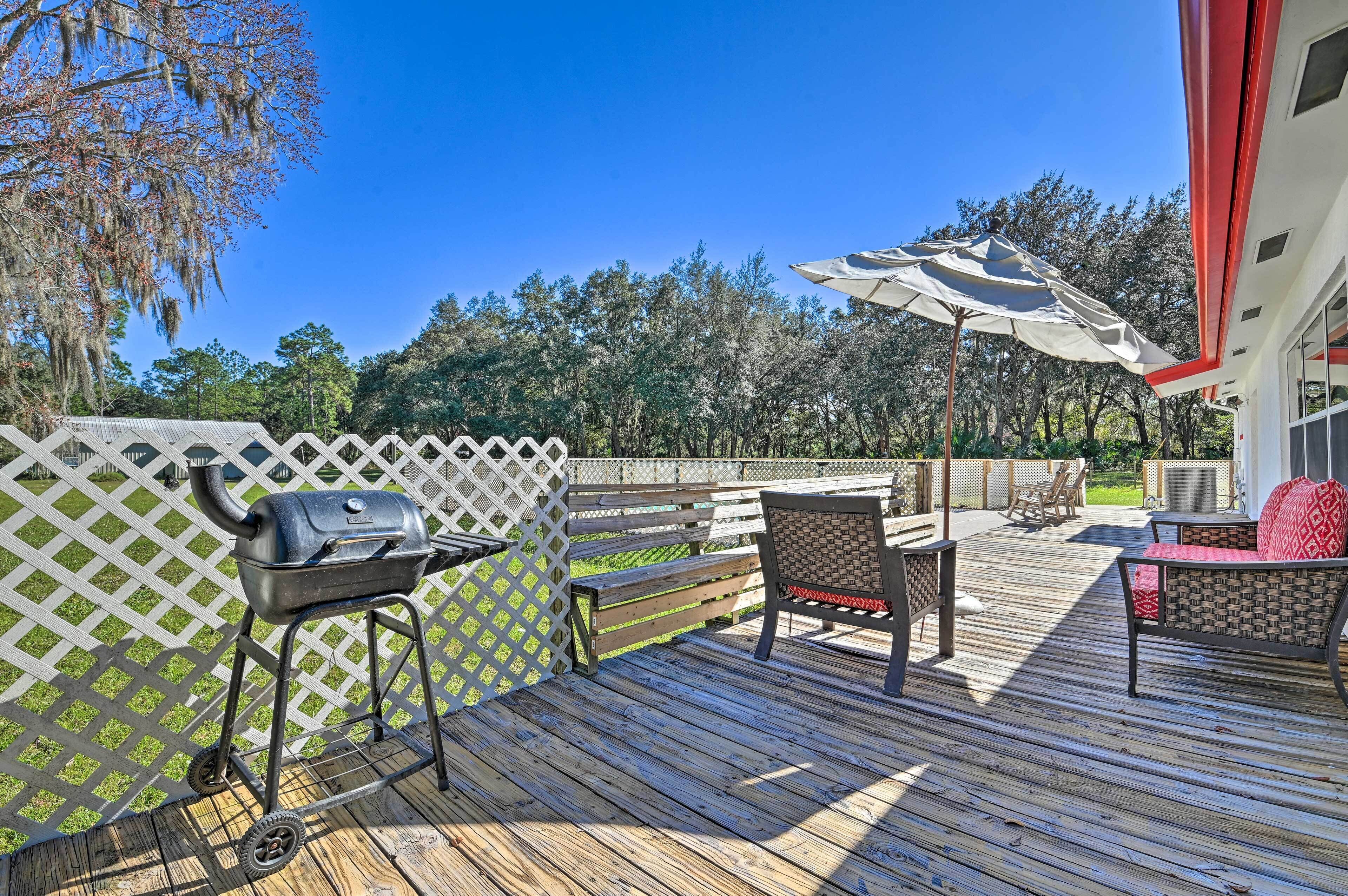 A wooden deck with a grill, outdoor furniture, and a white lattice fence.