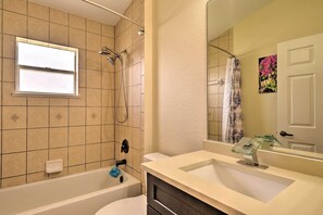 A bathroom with a bathtub, a shower, a sink, and a window. - Screened Patio: Canal-front Cape Coral Home (Cape Coral)