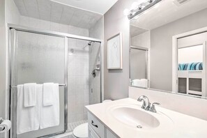 Une salle de bain moderne avec une douche à parois de verre, un lavabo blanc et un grand miroir.