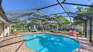 A covered swimming pool with a brick patio, surrounded by chairs and potted plants. - Private Pool + Covered Patio: Cape Coral Haven! (Cape Coral)