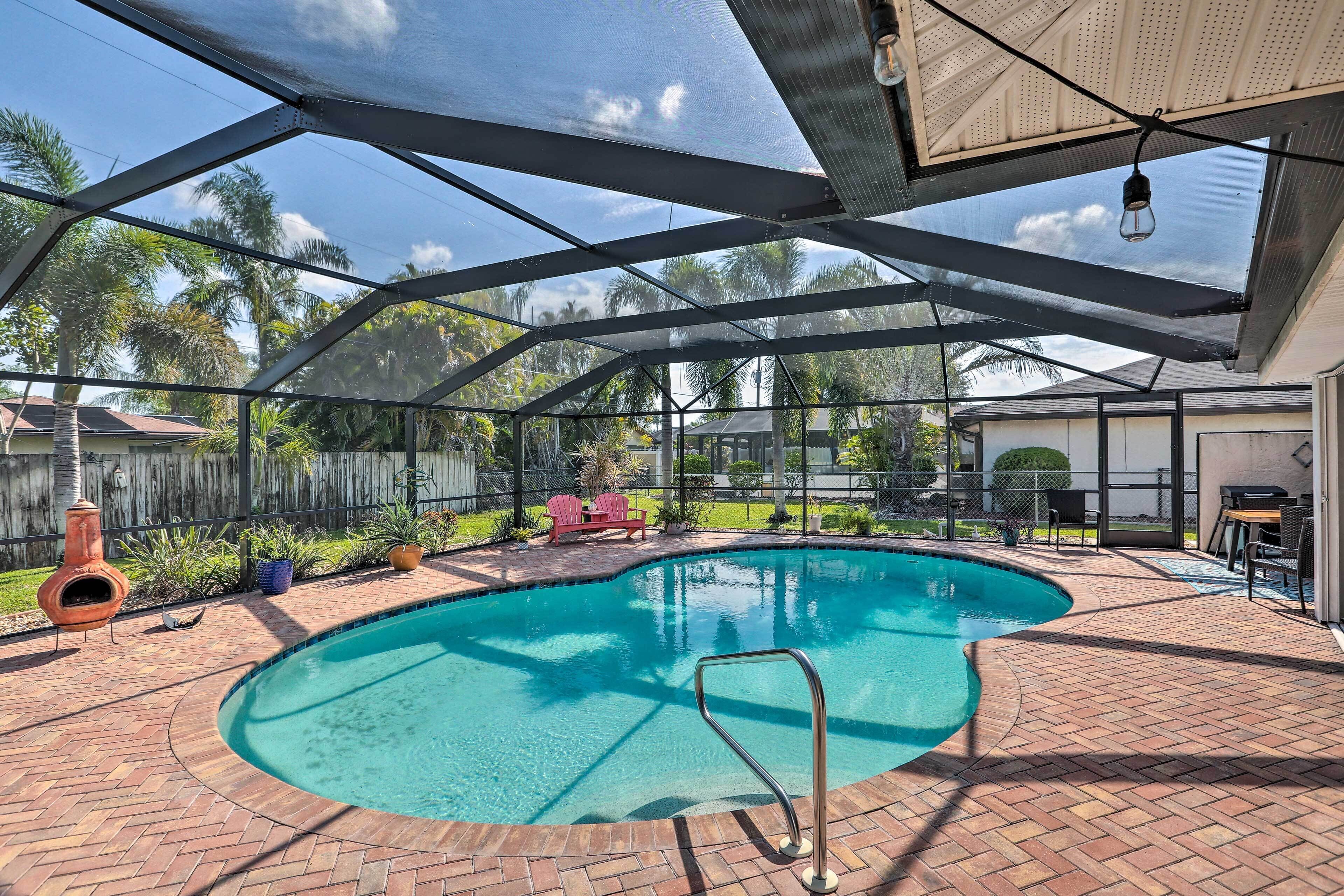 Ein Swimmingpool mit überdachter Terrasse, Grill und Feuerstelle.