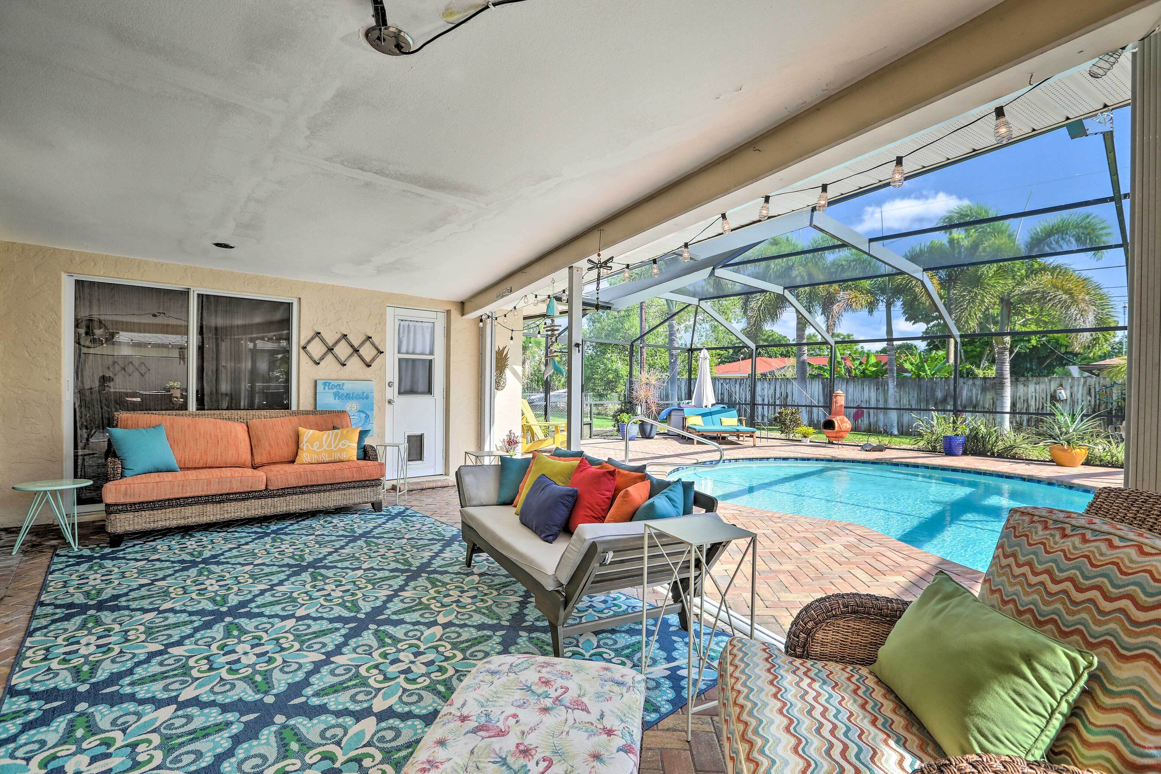 A sunlit indoor patio with a pool, outdoor furniture, and a view of the surrounding greenery.