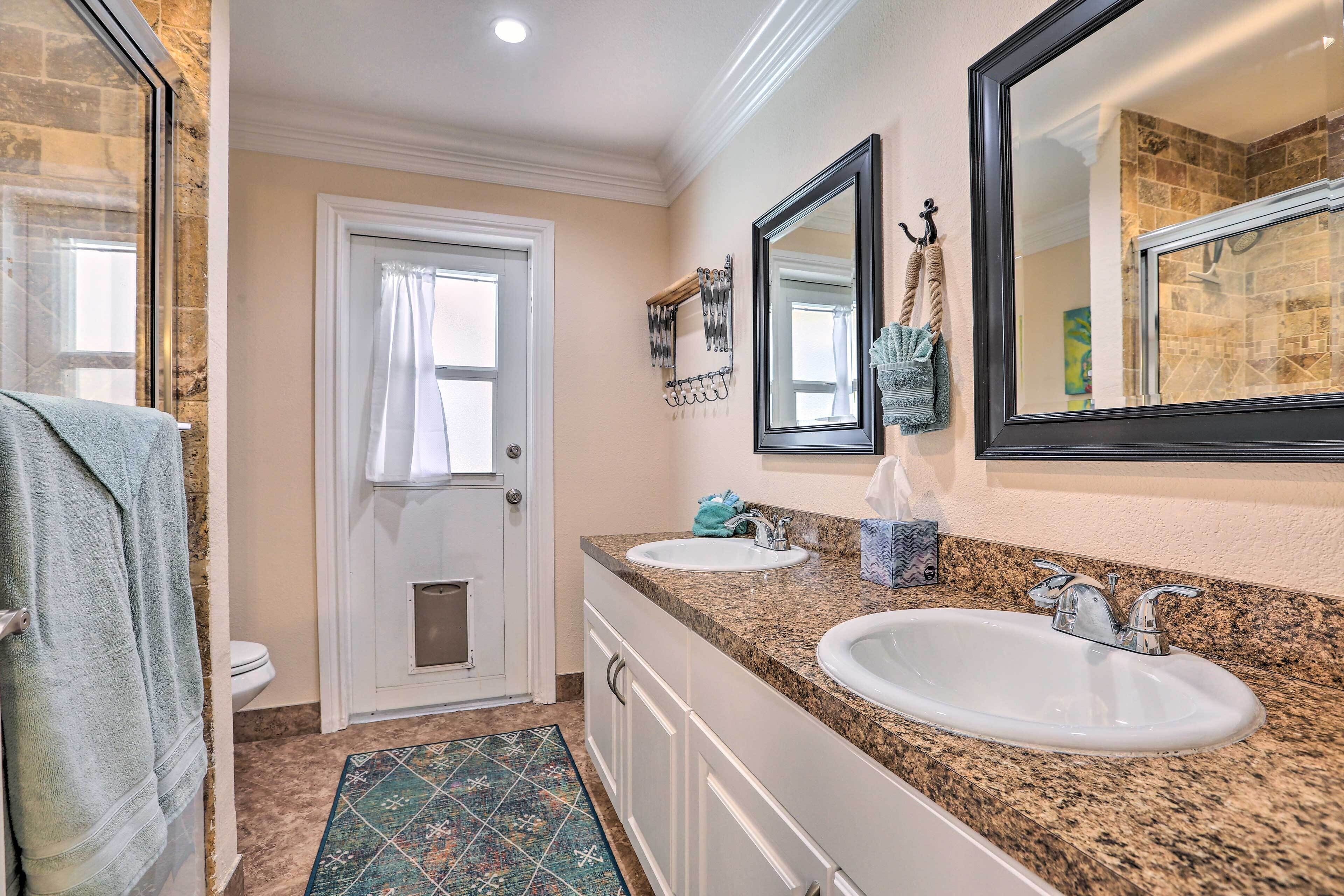 A bathroom with two sinks, a toilet, and a shower.