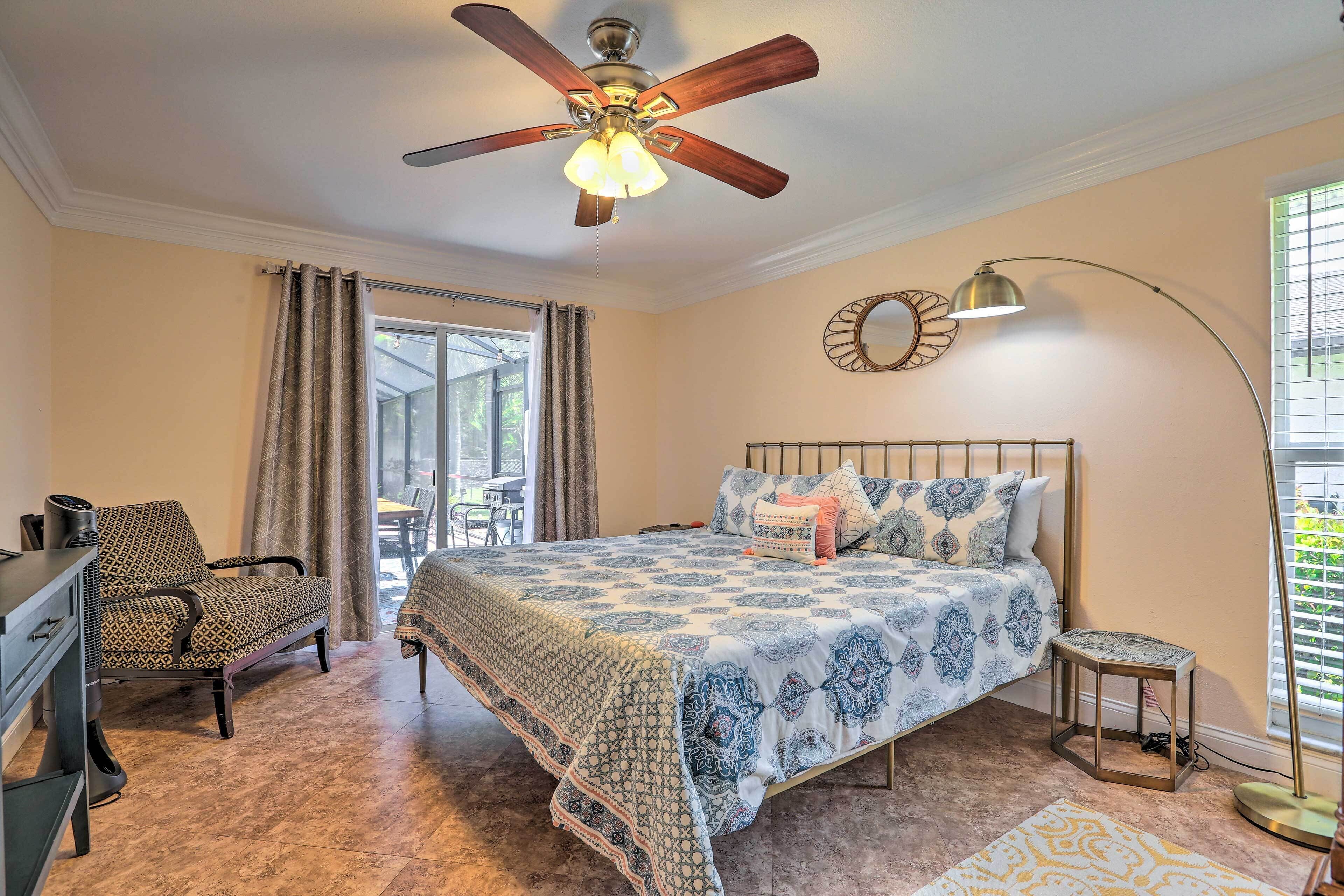 A bedroom with a bed, a desk, a chair, a ceiling fan, a lamp, and a window with blinds.