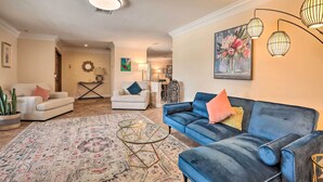 A living room with a blue sofa, a white sofa, a patterned rug, and a glass coffee table. - Private Pool + Covered Patio: Cape Coral Haven! (Cape Coral)