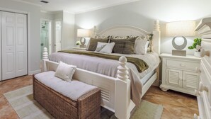 A bedroom with a bed, nightstands, a dresser, a wicker bench, and a door.