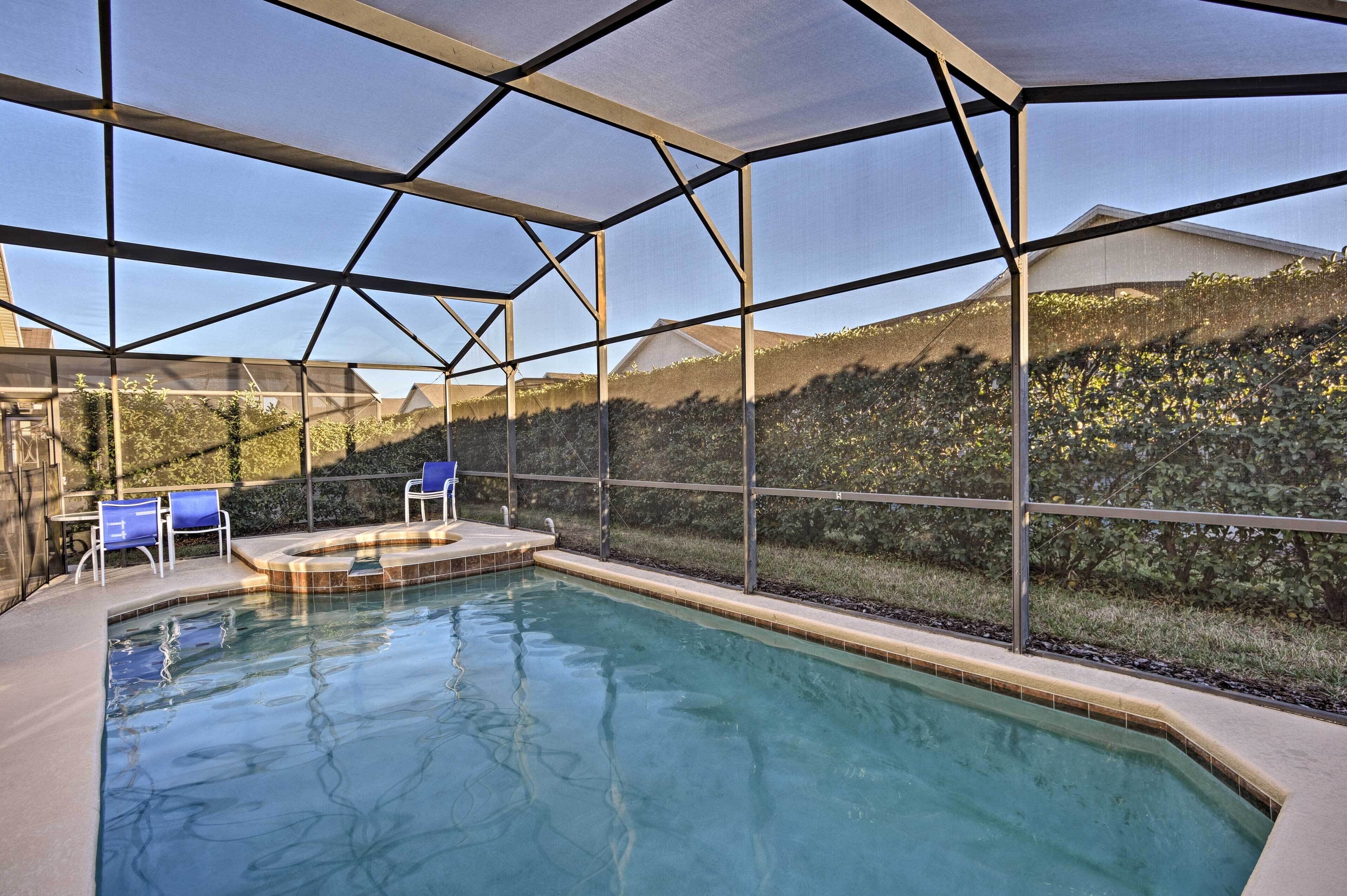 Une piscine intérieure offrant une vue dégagée sur le paysage environnant, un jacuzzi et deux chaises bleues.