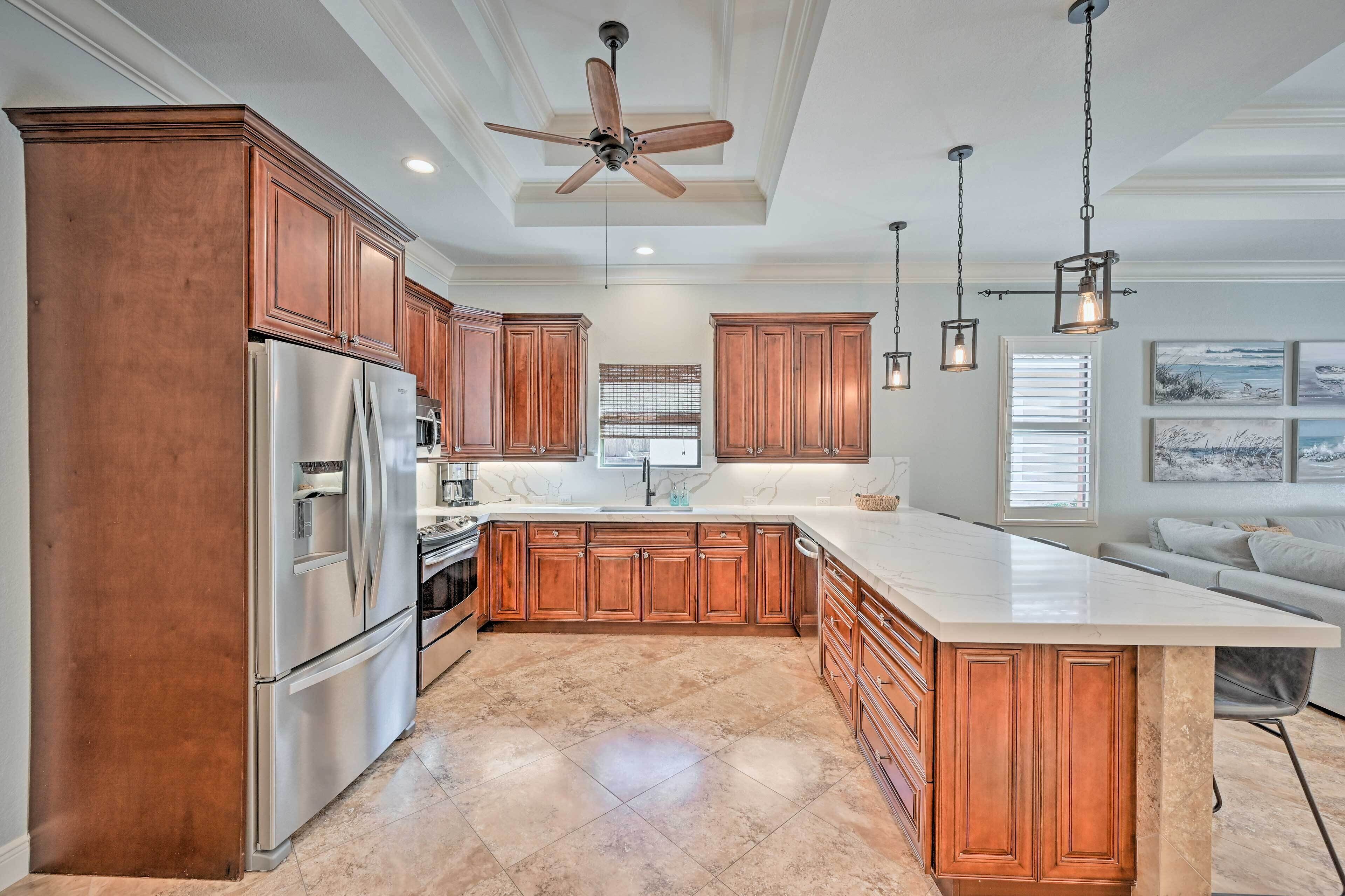 A spacious kitchen with wooden cabinets, a large island, stainless steel appliances, and pendant lighting.