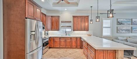 A spacious kitchen with wooden cabinets, a large island, stainless steel appliances, and pendant lighting.