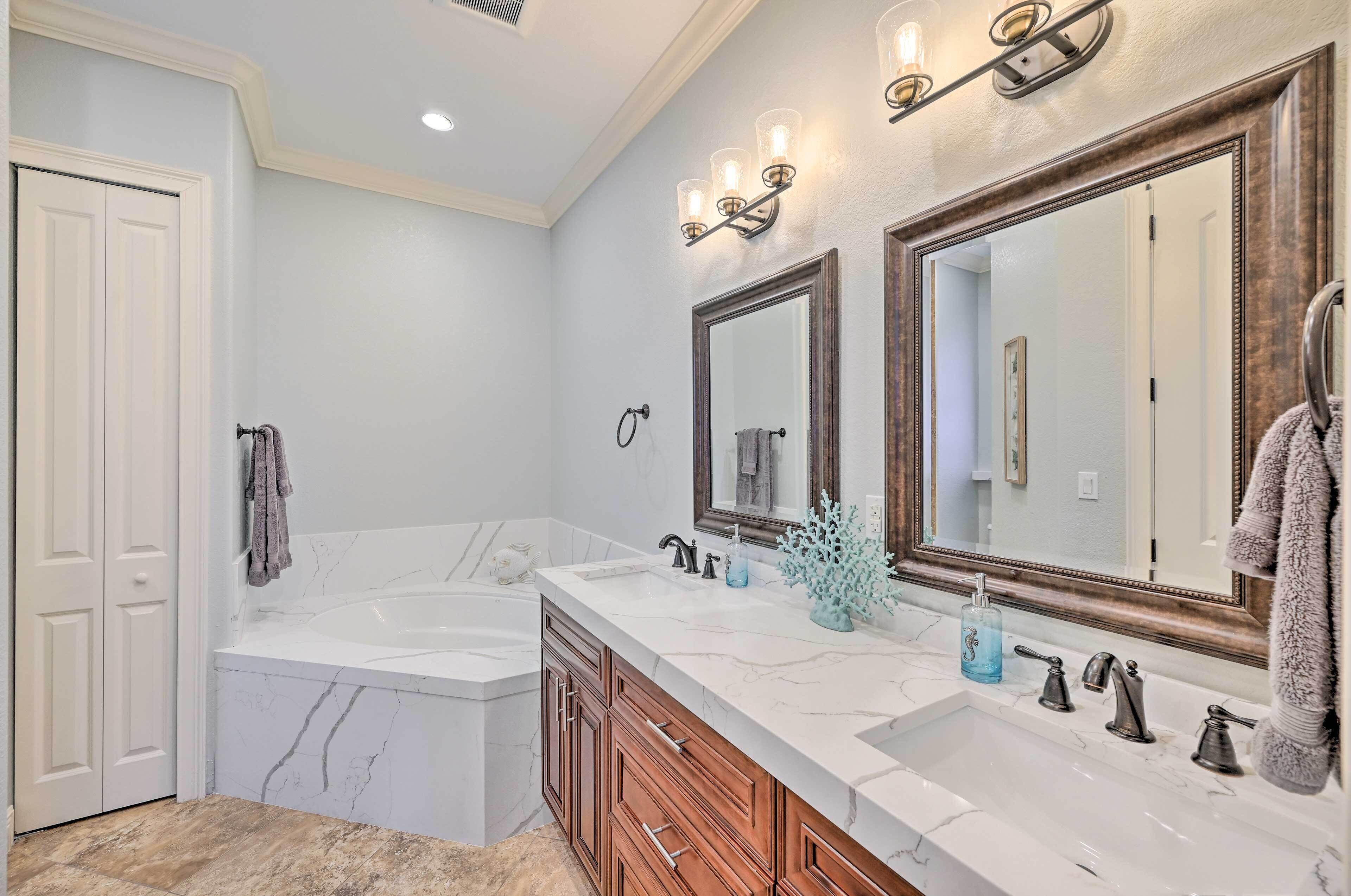 A bathroom with a double sink, a large mirror, and a bathtub.