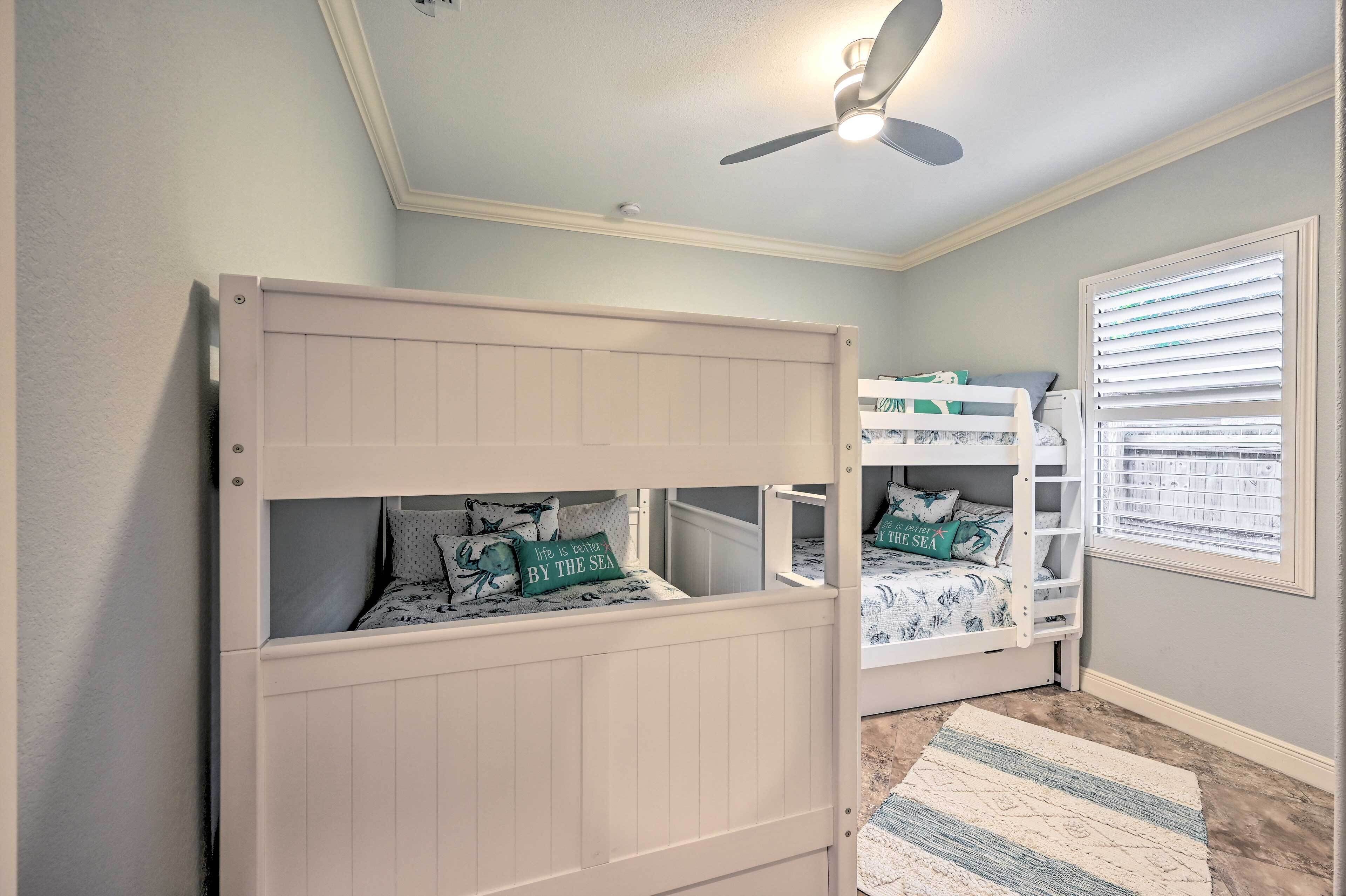 A child’s room with bunk beds, a ceiling fan, and a window with blinds.