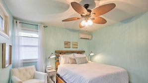 Un dormitorio con una cama grande, un ventilador de techo, una silla y una mesita de noche.