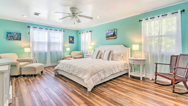 Quarto com cama, duas mesas de cabeceira, uma cadeira e piso de madeira.