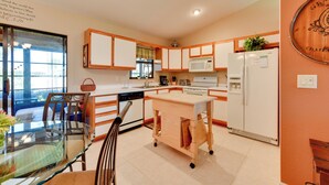 Una cucina moderna con mobili in legno, un tavolo da pranzo in vetro e un forno a microonde integrato.