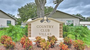 Segnale per Country Club Villas con un giardino curato di fronte.