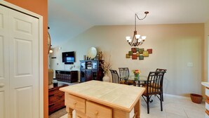 Un'area pranzo con tavolo e sedie in legno, un lampadario e una TV a parete.