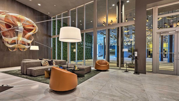 A modern lobby with a large abstract art piece, comfortable seating, and large windows offering views of the outdoors. - Chic Miami Condo w/ Pool, 6 Mi to South Beach (Miami)