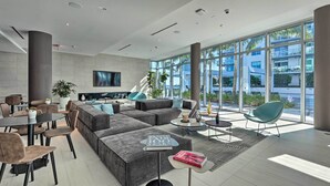A modern hotel lobby with a large sectional sofa, a dining area, and a TV mounted on the wall. - Chic Miami Condo w/ Pool, 6 Mi to South Beach (Miami)