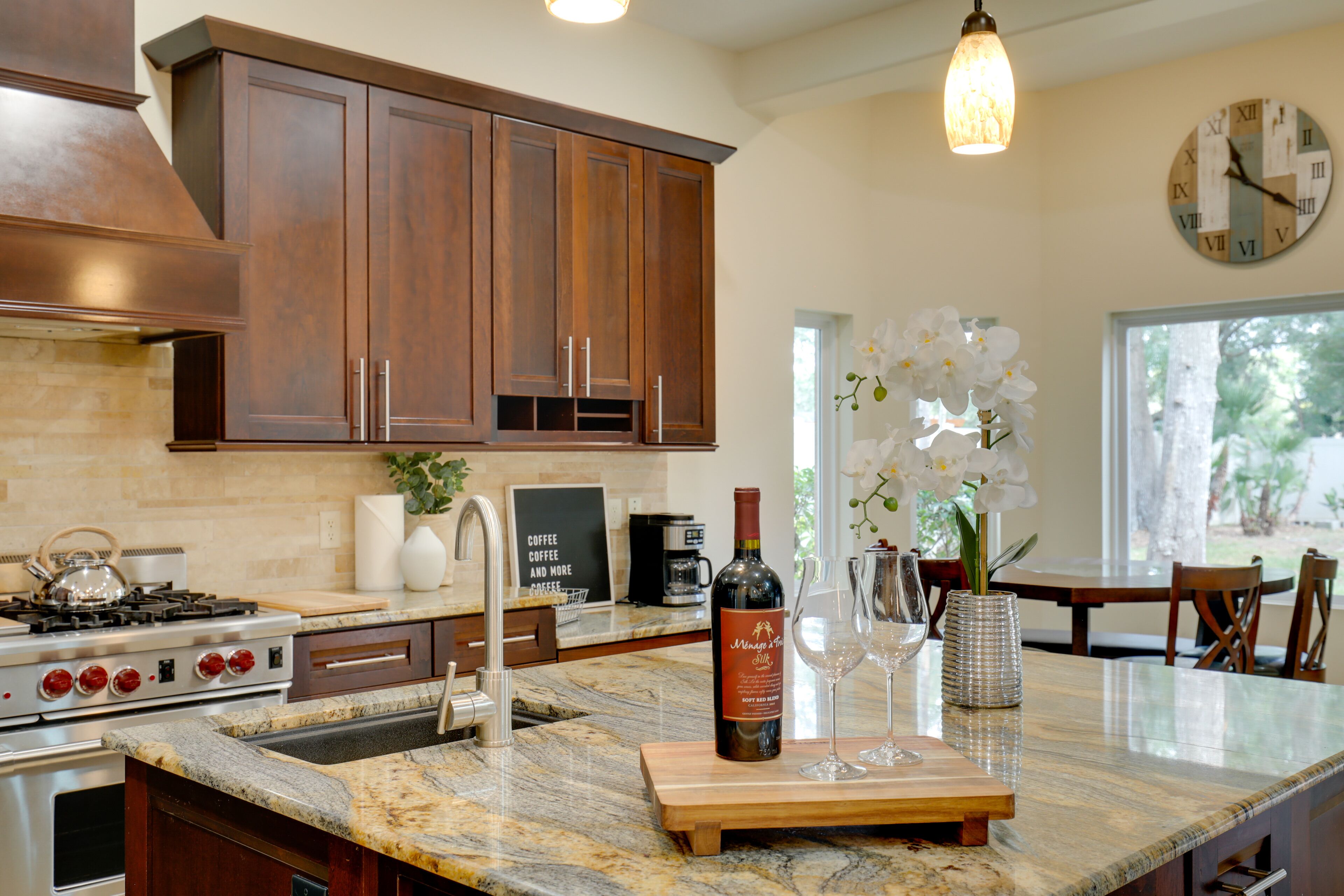 A kitchen with wooden cabinets, a gas stove, a coffee machine, and a wine bottle on the counter.