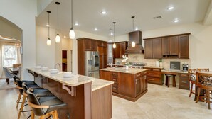 A spacious kitchen with a large island, wooden cabinets, and modern pendant lighting. - Contemporary Brandon Home w/ Pool & Game Room (Brandon)